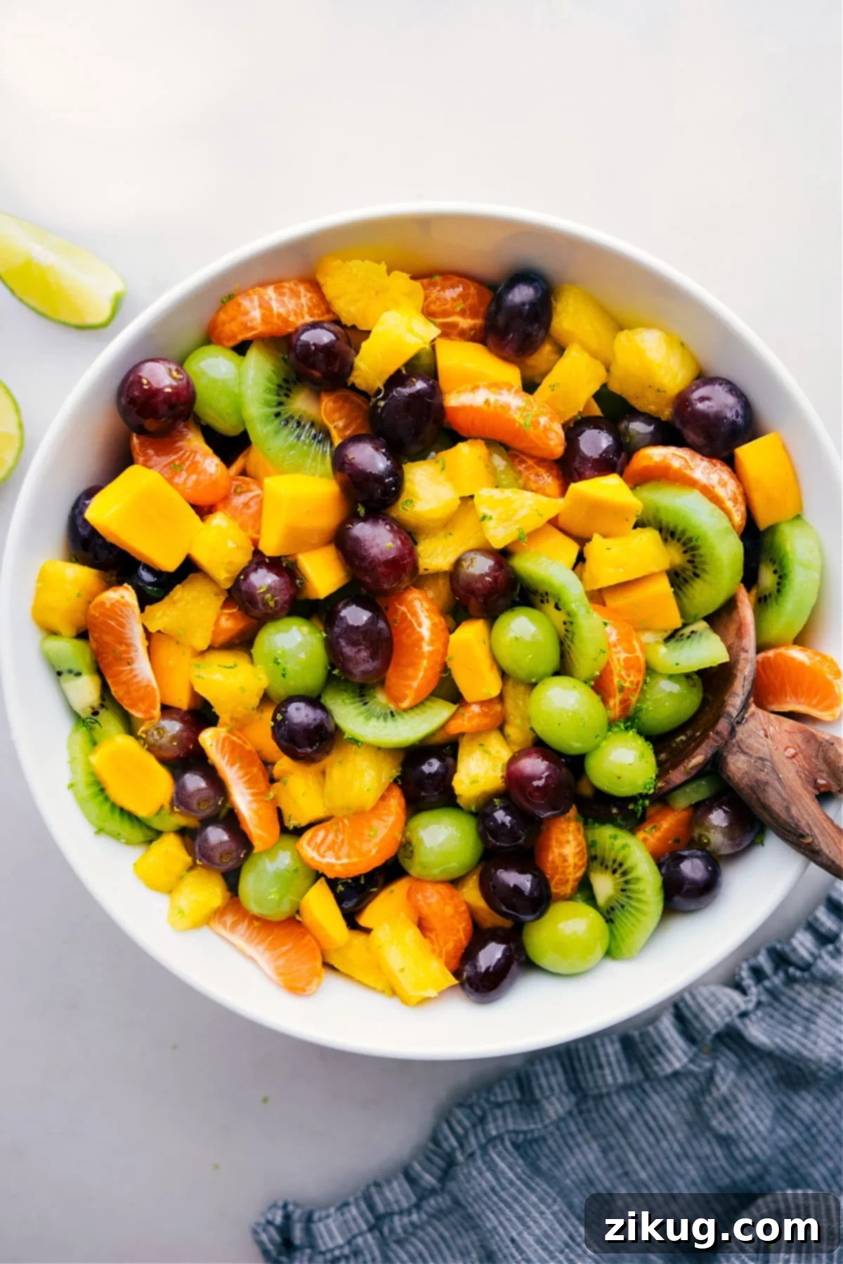 Tropical Fruit Salad A large bowl filled with vibrant Tropical Fruit Salad, featuring chunks of mango, kiwi, pineapple, and colorful grapes.