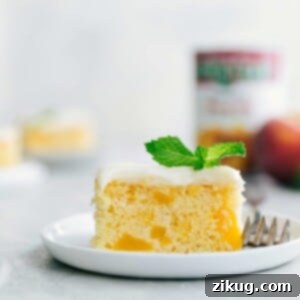 Close-up of a slice of Peaches and Cream Cake, revealing its moist texture, peach chunks, and generous layer of cream cheese frosting.