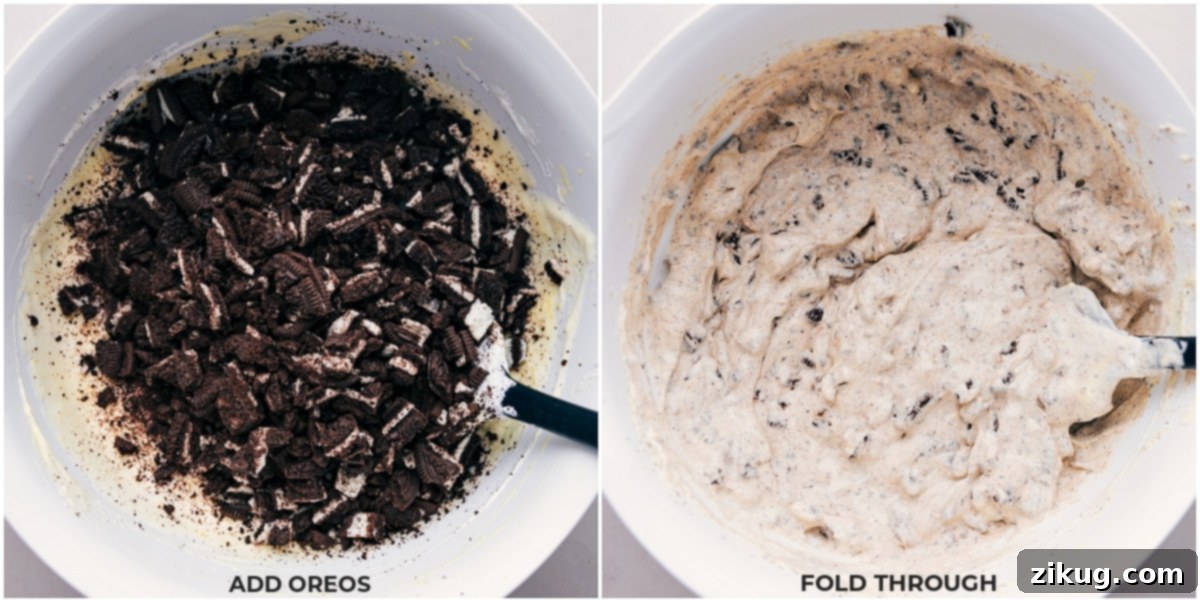 Crushed Oreos being gently folded into the creamy white fluff mixture in a bowl.