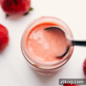 A close-up shot of the finished Strawberry Balsamic Vinaigrette presented in an elegant glass jar, showcasing its beautiful vibrant pink hue and inviting, smooth texture.