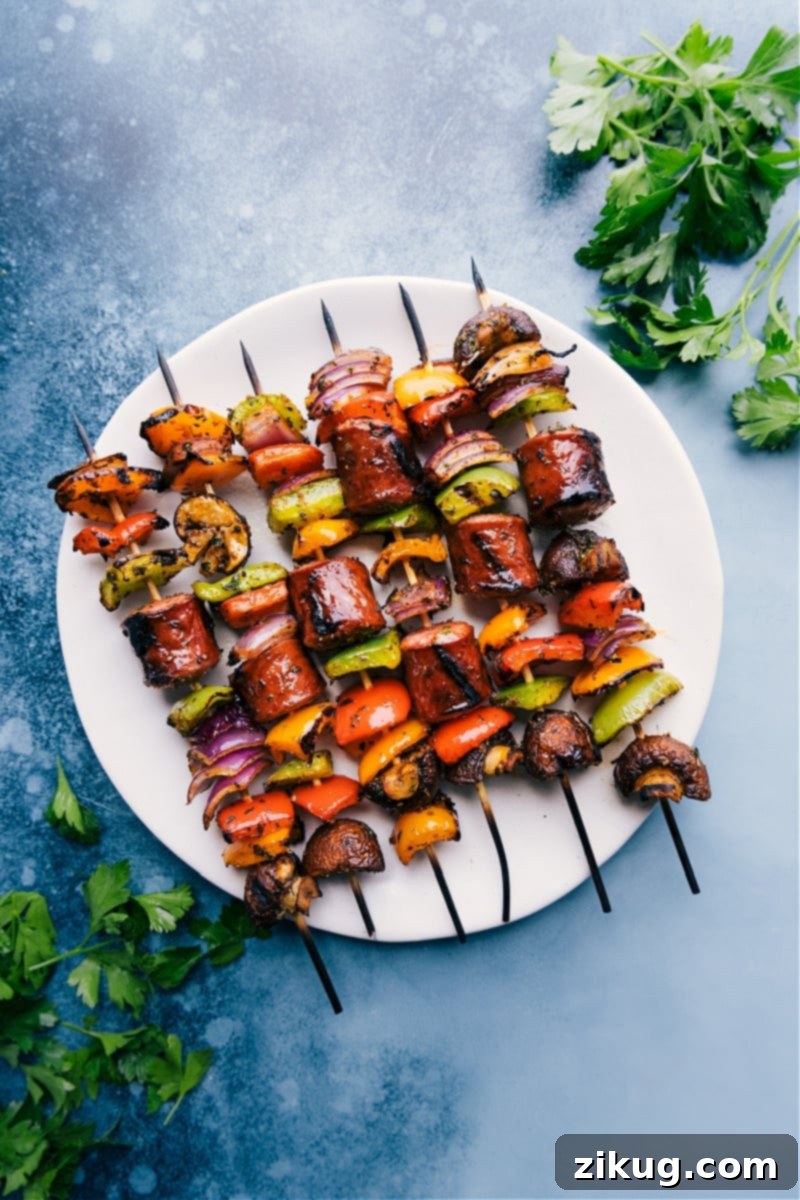Sausage Kabobs are simple to make, nutritious, and loaded with flavor! Recipe via ChelseasMessyApron #dinner #quick #easy #healthy #whole #whole30 #keto #veggies #grilled #summer #sausage #kabobs Overhead image of the vibrant, grilled sausage kabobs served on a plate with fresh parsley garnish.