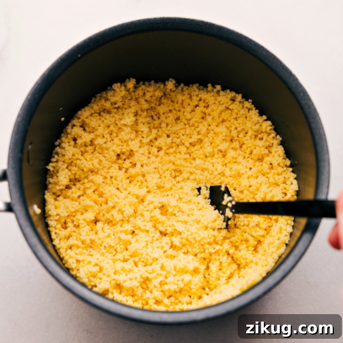 Fluffy couscous, perfectly cooked and ready to be incorporated into the Mediterranean salad, shown in its pot.