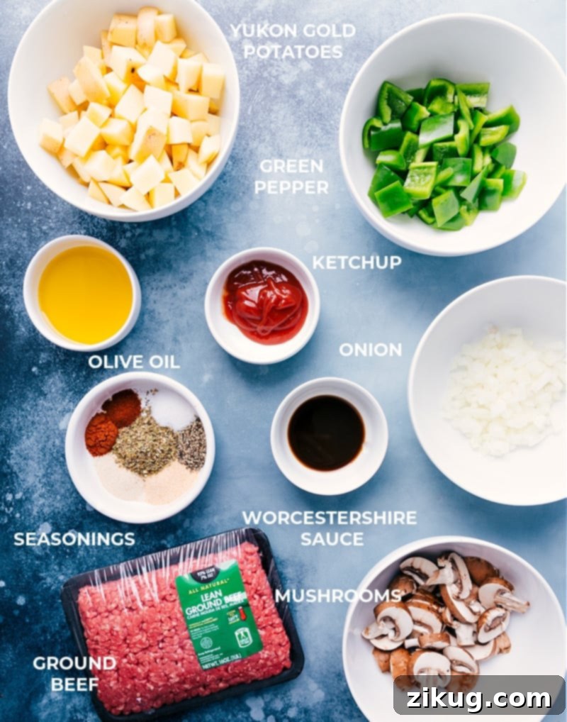 A selection of fresh ingredients including ground beef, potatoes, bell peppers, onions, and mushrooms for Philly Cheesesteak Foil Packs. Ingredients for Philly Cheesesteak Foil Packs laid out on a cutting board.