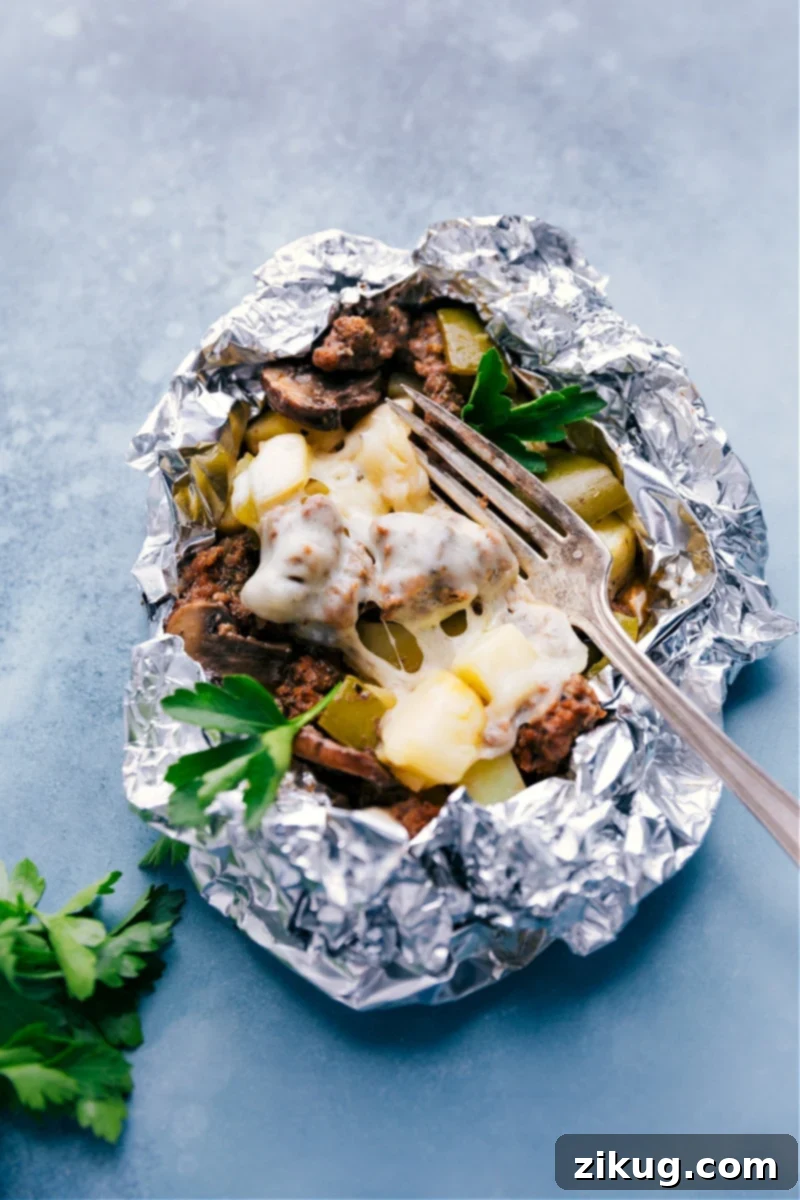 A perfectly cooked Philly Cheesesteak Foil Pack, showcasing the melted Provolone over a hearty mix of beef and vegetables. Close-up of a cooked Philly Cheesesteak Foil Pack with melted Provolone cheese.