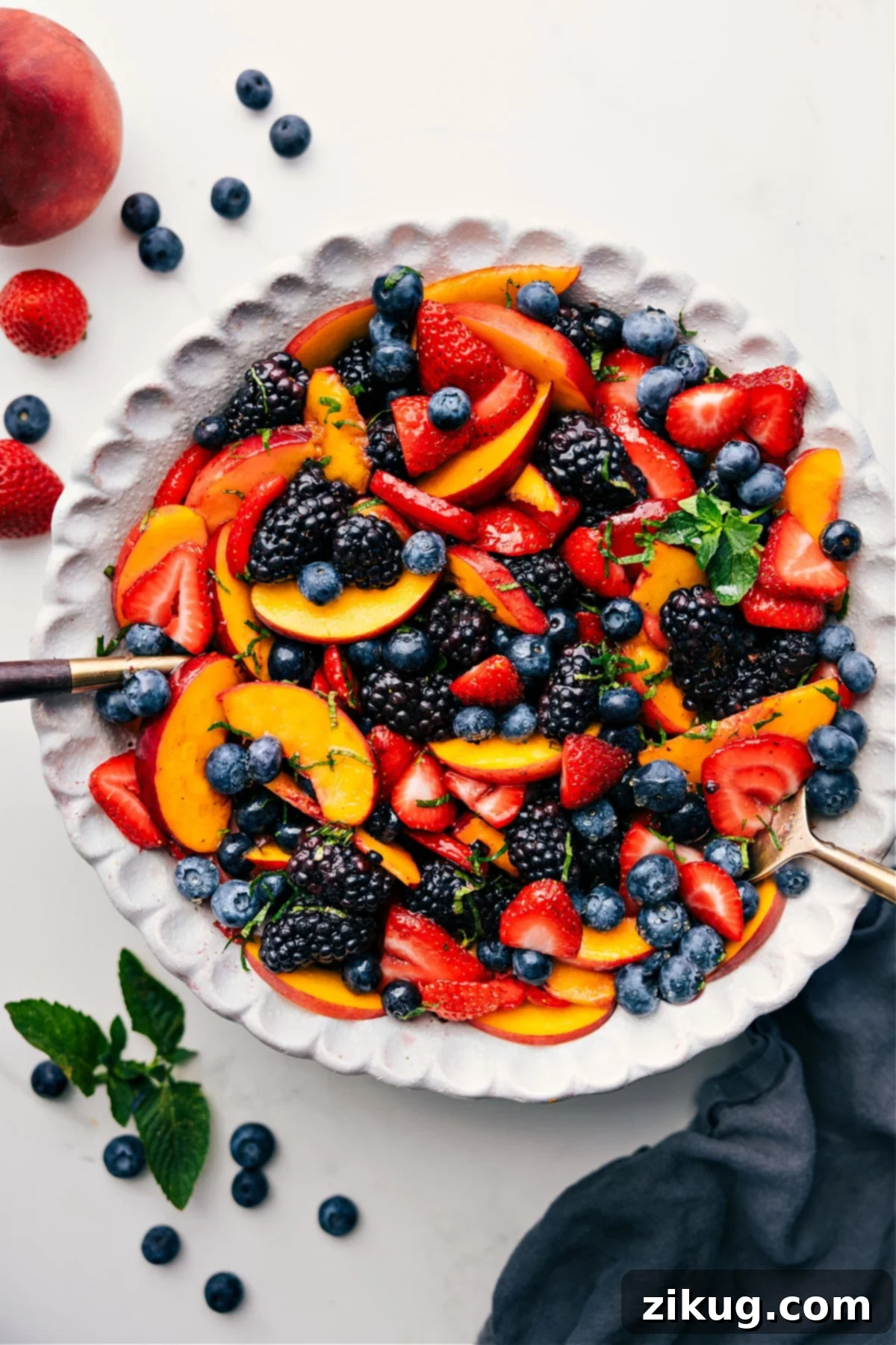 A vibrant Peach Fruit Salad tossed together with fresh berries and a glistening citrus dressing, ready to be served in a large bowl.