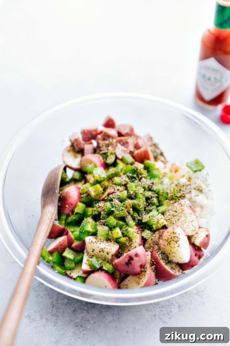 How To Make Sausage And Potato Foil Packs All the veggies, sausages, and seasonings added to a bowl to toss together.
