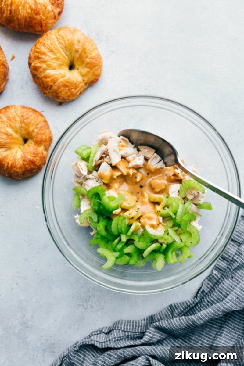 Prepare the Best Honey Mustard Chicken Salad for Quick Lunches An overhead shot showcasing a bowl of the Honey Mustard Chicken Salad mixture, perfectly combined and ready to be served, with golden-brown croissant rolls enticingly placed nearby, suggesting the ideal serving option.