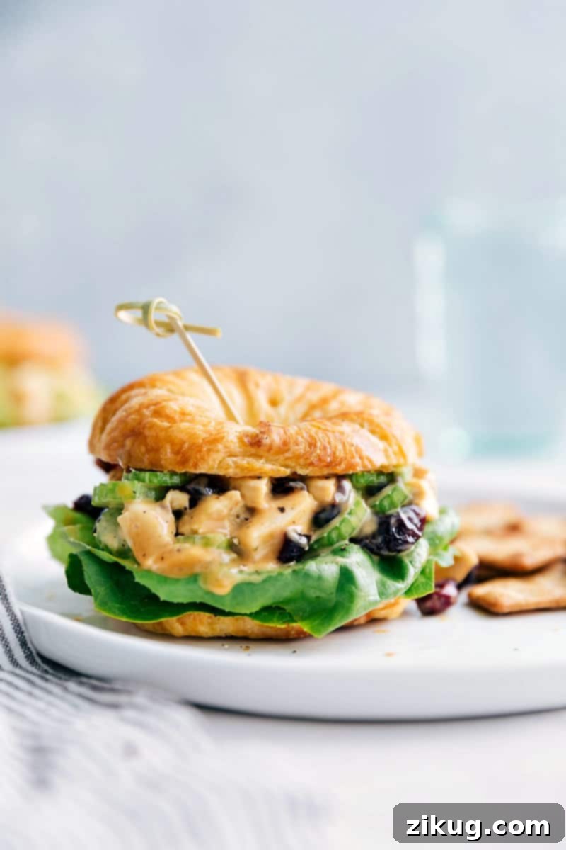 Perfect Honey Mustard Chicken Salad Sandwich for Any Meal A vibrant close-up of a finished Honey Mustard Chicken Salad Sandwich, showcasing its hearty filling and fresh lettuce on a croissant, accompanied by crackers. This highlights the readiness to enjoy a fulfilling meal.