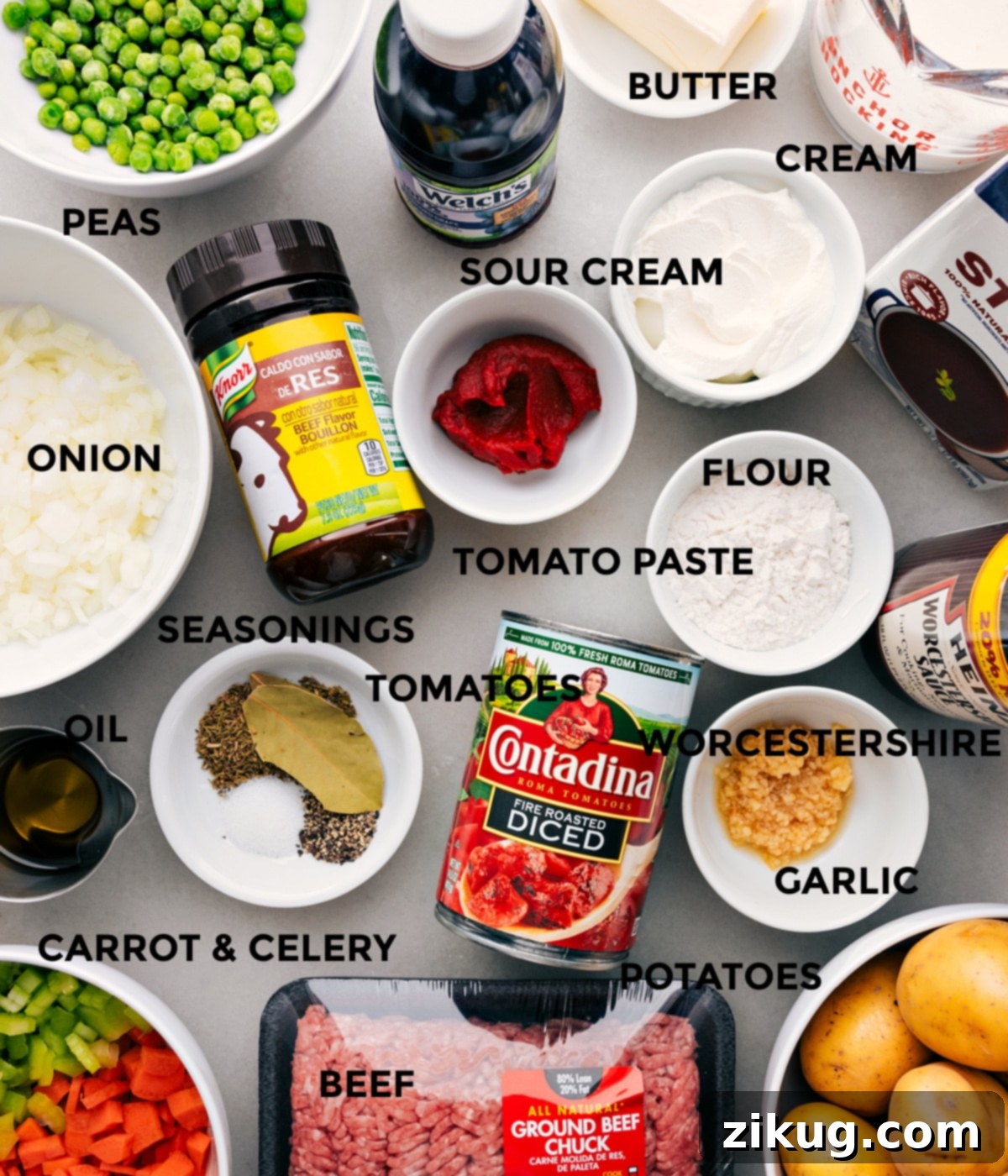 All the ingredients in this recipe prepped out for easy assembly including the peas, onions, seasonings, tomatoes, sour cream, tomato paste, grape juice, butter, cream, stock, flour, Worcestershire, garlic, potatoes, and beef.