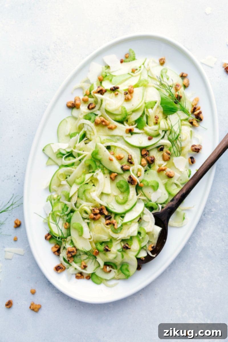 A light and tangy Apple Fennel Salad with thinly sliced apples, celery, and fennel topped with walnuts and Parmigiano Reggiano PDO Overhead shot of a vibrant Apple Fennel Salad with walnuts and parmesan