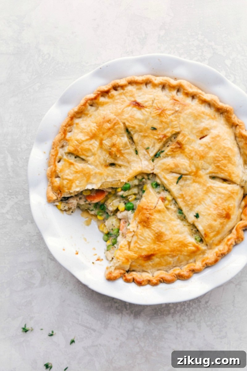 A golden, flaky-crusted turkey pot pie fresh from the oven, with a hearty serving already scooped out, highlighting its comforting filling.