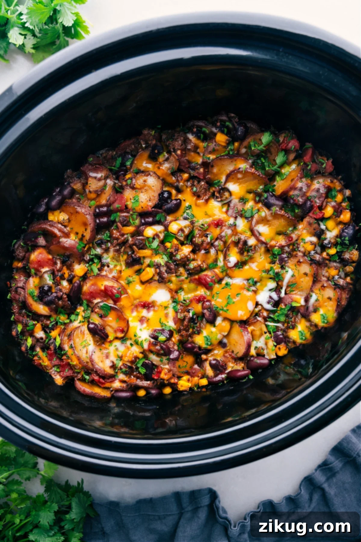 The Best Crockpot Cowboy Casserole Recipe Crockpot Cowboy Casserole with freshly grated and melted cheese on top, still in the crockpot.