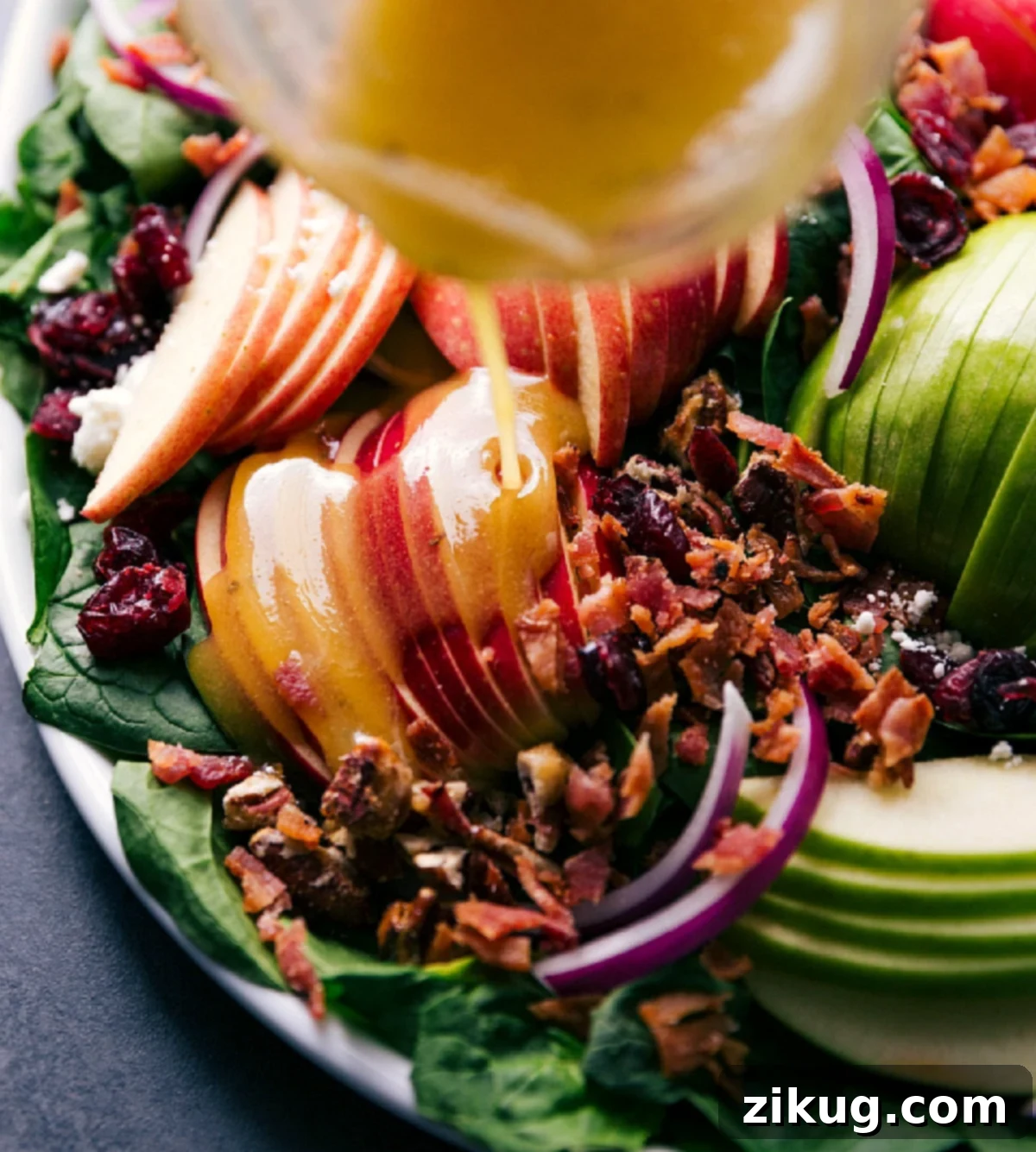 Vibrant Spinach Salad 7 Homemade Apple Dijon Vinaigrette being drizzled generously over the vibrant Spinach Salad.