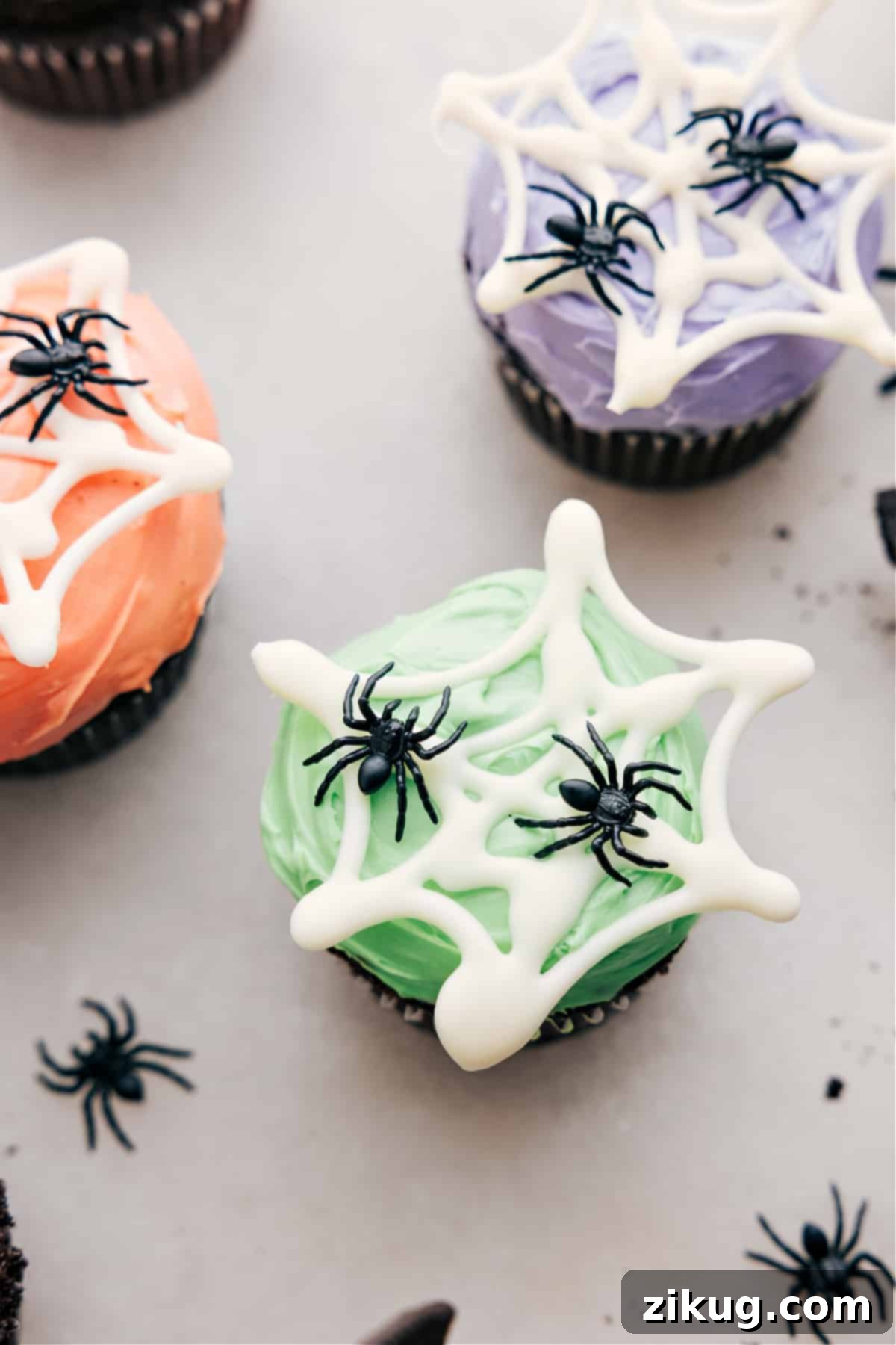 Close-up of a spider web design on colored frosting with fake spiders, ready for Halloween festivities.