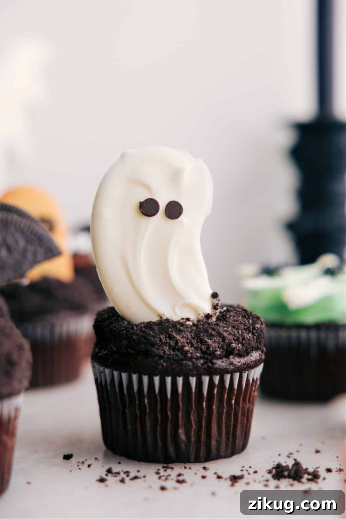 Whimsical ghost Halloween cupcakes featuring white chocolate ghosts with mini chocolate chip eyes, standing atop frosted cupcakes.