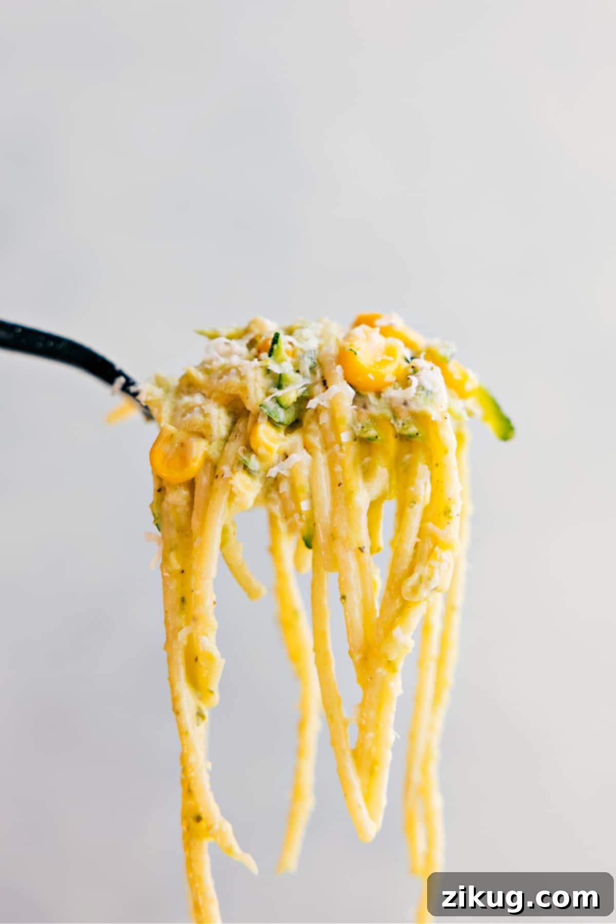 A forkful of the pasta being held up showing all the yummy components to it.