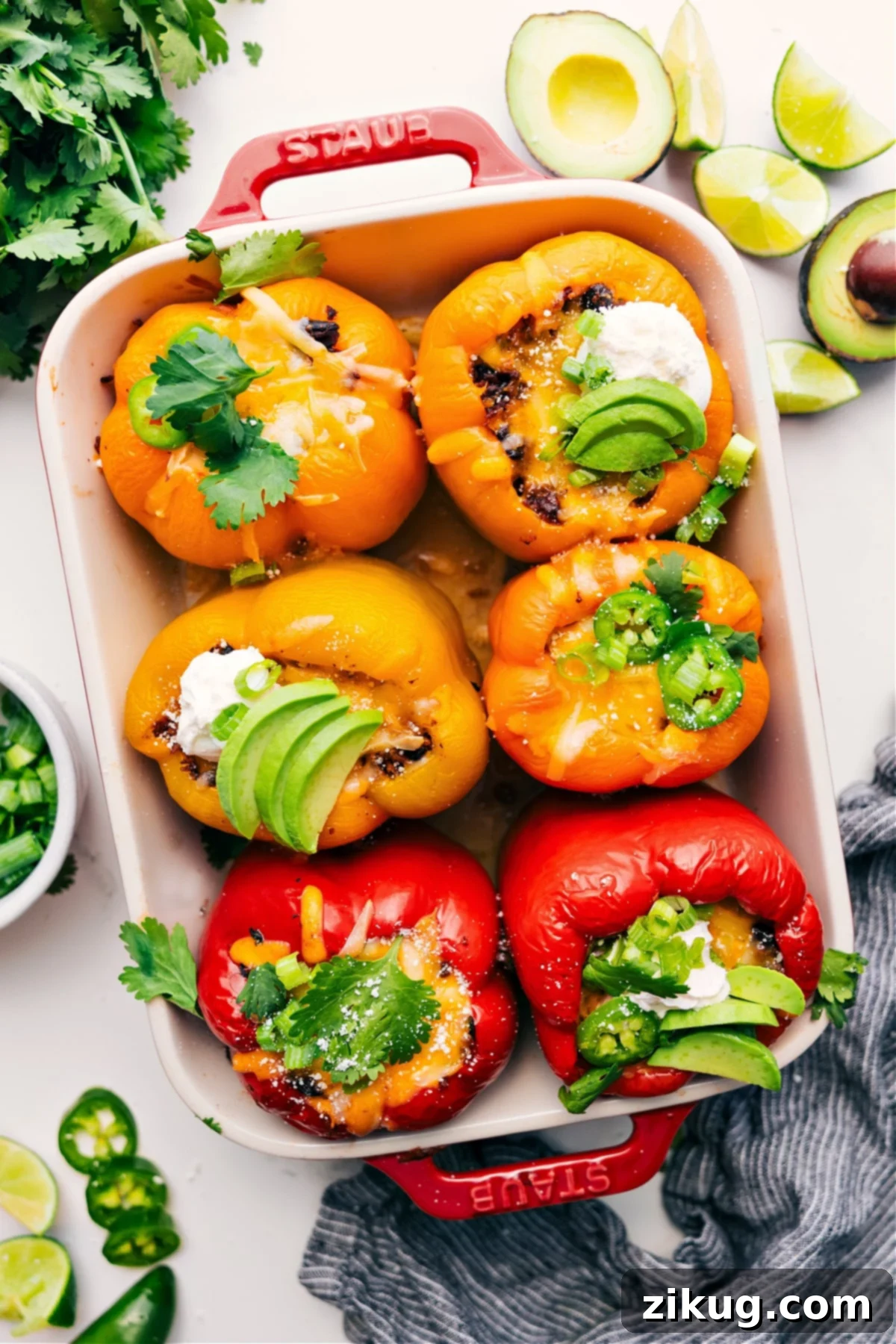 Irresistible Mexican Stuffed Peppers: Your New Favorite Low-Carb Weeknight Dinner Mexican stuffed peppers in a pan topped with fresh cilantro, sliced jalapeños, sour cream, and avocado pieces, ready to be served.