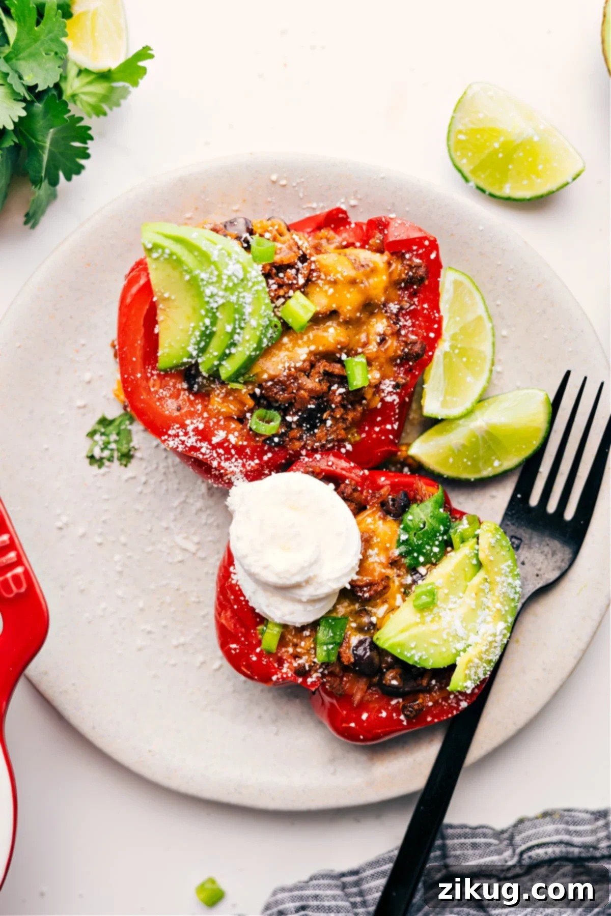 Mexican Stuffed Peppers with All the Yummy Toppings A Mexican stuffed pepper cut in half, showcasing the rich filling, and topped generously with sour cream, fresh avocado slices, cilantro, and jalapeños, ready to be enjoyed as a flavorful and hearty dinner.