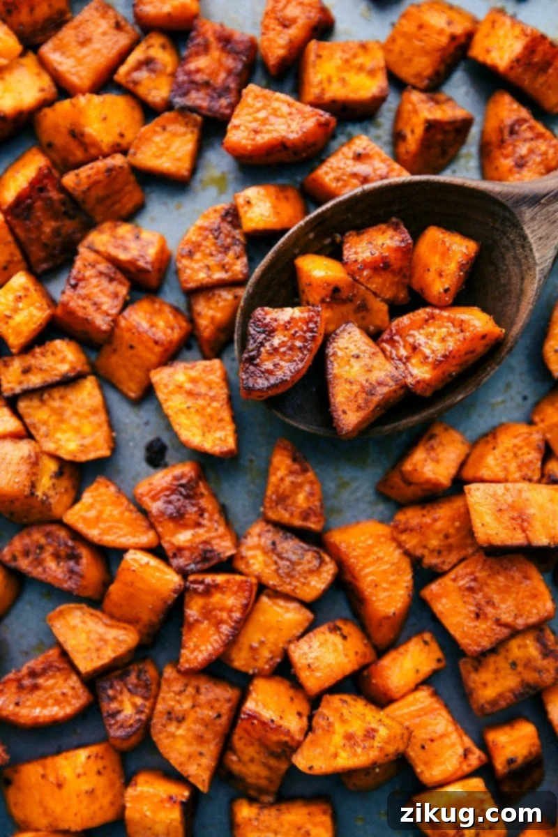 Delicious roasted sweet potatoes, perfectly cooked and ready to eat as a fantastic side dish or meal component. Finished roasted sweet potatoes proudly displayed on a sheet pan, ready to be enjoyed.