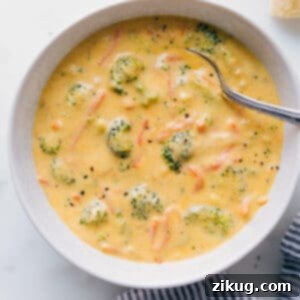 A close-up of a generous serving of creamy Homemade Broccoli Cheddar Soup in a rustic bowl, garnished with shredded cheese.