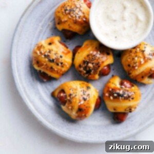 A top-down view of a platter filled with freshly baked, golden everything bagel pigs in a blanket, ready to be served.
