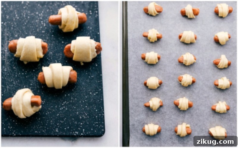 Process shot of unbaked pigs in a blanket arranged on a parchment-lined baking sheet, showcasing the rolled crescent dough and cocktail franks.