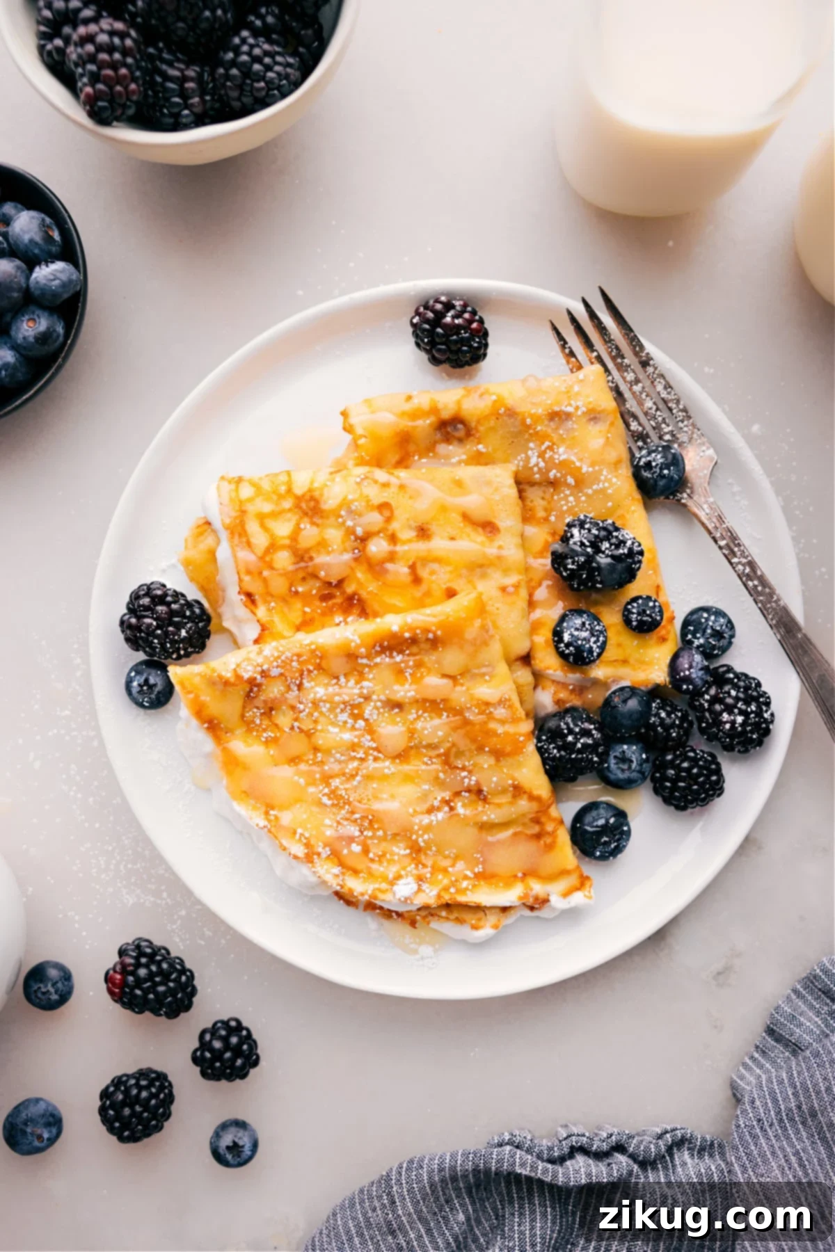 Plateful of delicious crepes with fresh berries and a dusting of powdered sugar, ready to be enjoyed.