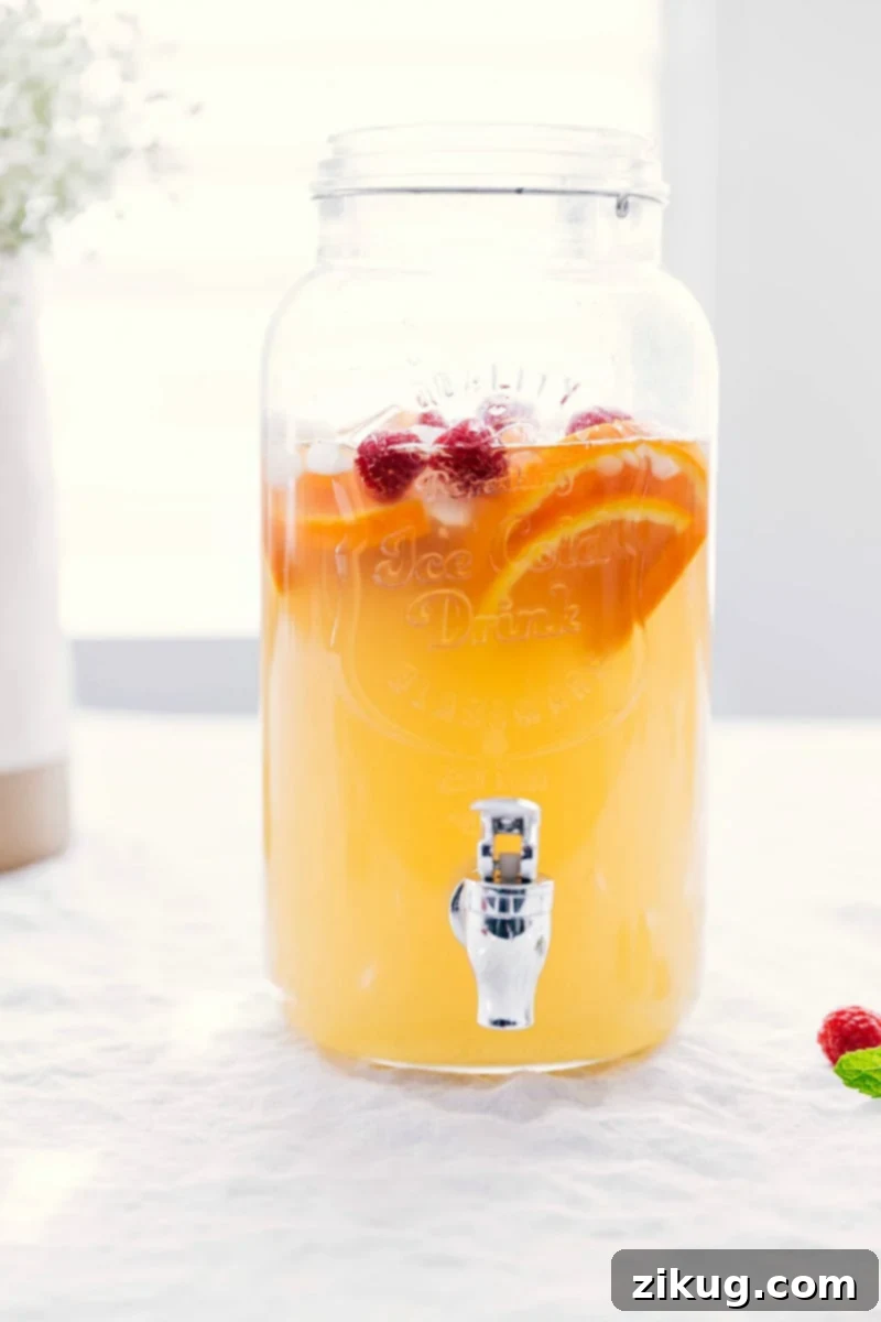 Refreshing White Grape Punch in Dispenser with Fresh Fruit Ready-to-drink white grape punch in an elegant drink dispenser, adorned with fresh fruit slices and berries for a beautiful and delicious presentation.