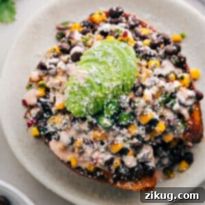 Close-up of a perfectly stuffed sweet potato with Southwestern topping and creamy sauce.