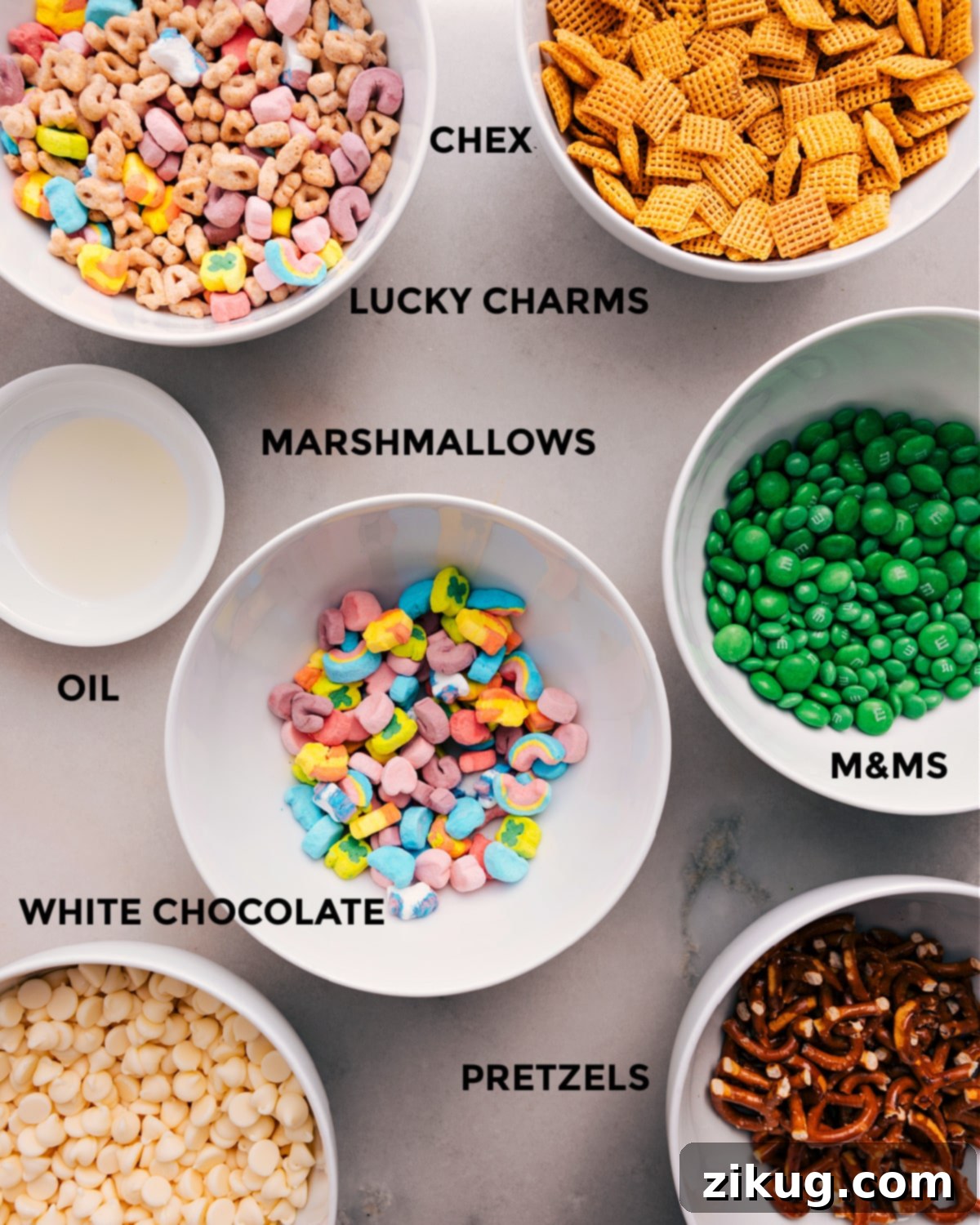 Ingredients In Leprechaun Bait Recipe All the essential ingredients for creating delicious Leprechaun Bait are neatly prepped and ready for easy assembly, including crispy Chex cereal, colorful Lucky Charms, festive green M&Ms, soft marshmallows, light oil, smooth white chocolate, and crunchy pretzels.