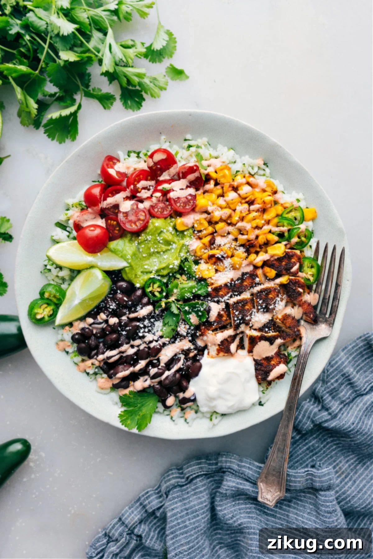 High Protein Burrito Bowl Recipe A vibrant and colorful chicken burrito bowl, loaded with seasoned chicken, cilantro-lime rice, black beans, corn, diced avocado, tomatoes, and a drizzle of creamy chili-lime sauce, ready to be enjoyed.
