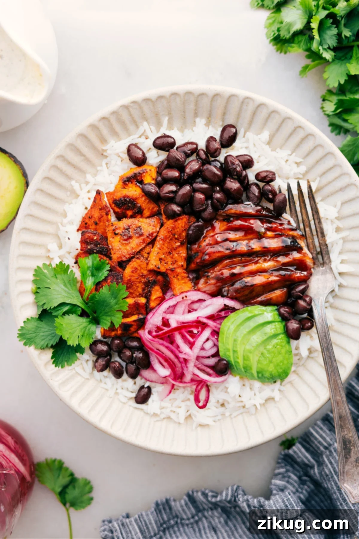 The Best Sweetgreen Copycat BBQ Chicken Bowl Recipe for Healthy Eating A vibrant BBQ Chicken Bowl with fluffy rice, saucy chicken, roasted sweet potatoes, pickled onions, avocado, and black beans, drizzled generously with green goddess dressing.