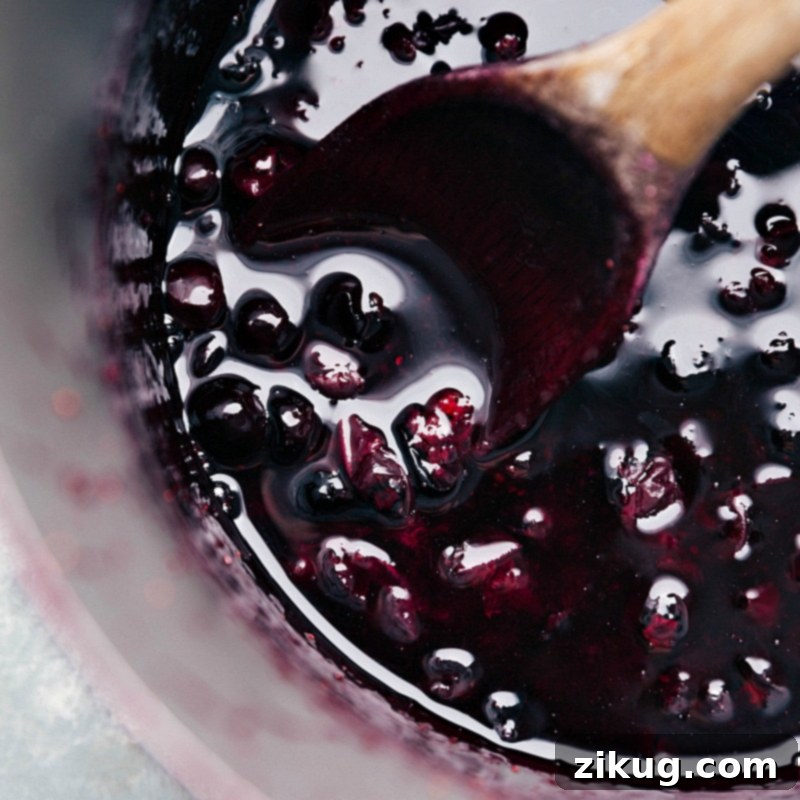 The Best Blueberry Syrup Blueberry Syrup on a wooden spoon, still in the saucepan.