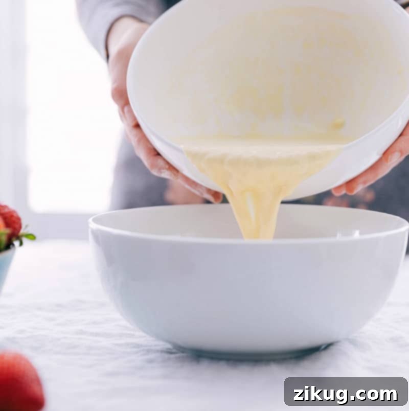 The perfect consistency for our all-time favorite Waffle Recipe Wet ingredients being carefully added to the dry ingredients in a bowl for the waffle batter.
