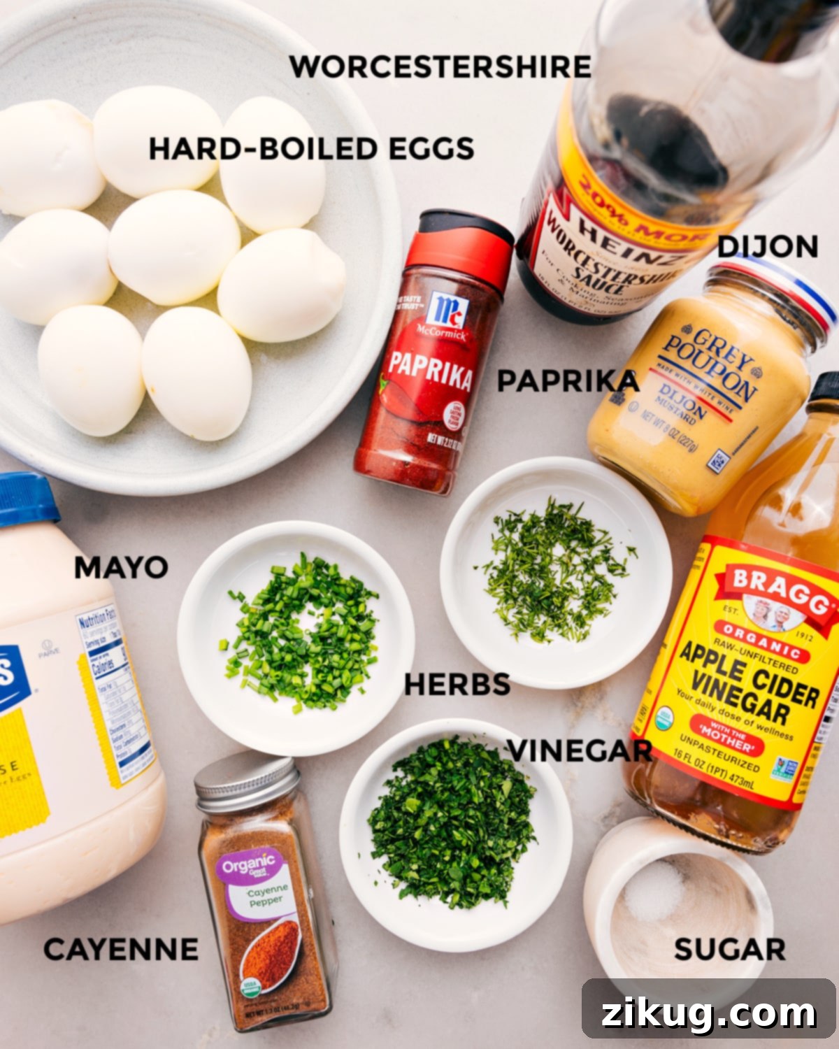 All the ingredients for this recipe are prepped and ready for easy assembly: eggs, Dijon, paprika, vinegar, herbs, mayo, seasonings, and sugar.