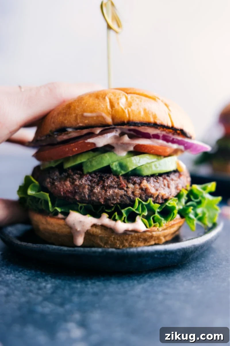 A stunning, gourmet black bean burger presented beautifully on a toasted, buttered bun, artfully arranged with vibrant fresh vegetables like lettuce, tomato, and avocado slices.