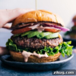 Gorgeous finished black bean burger with fresh vegetables sandwiched between a beautiful buttered bun.
