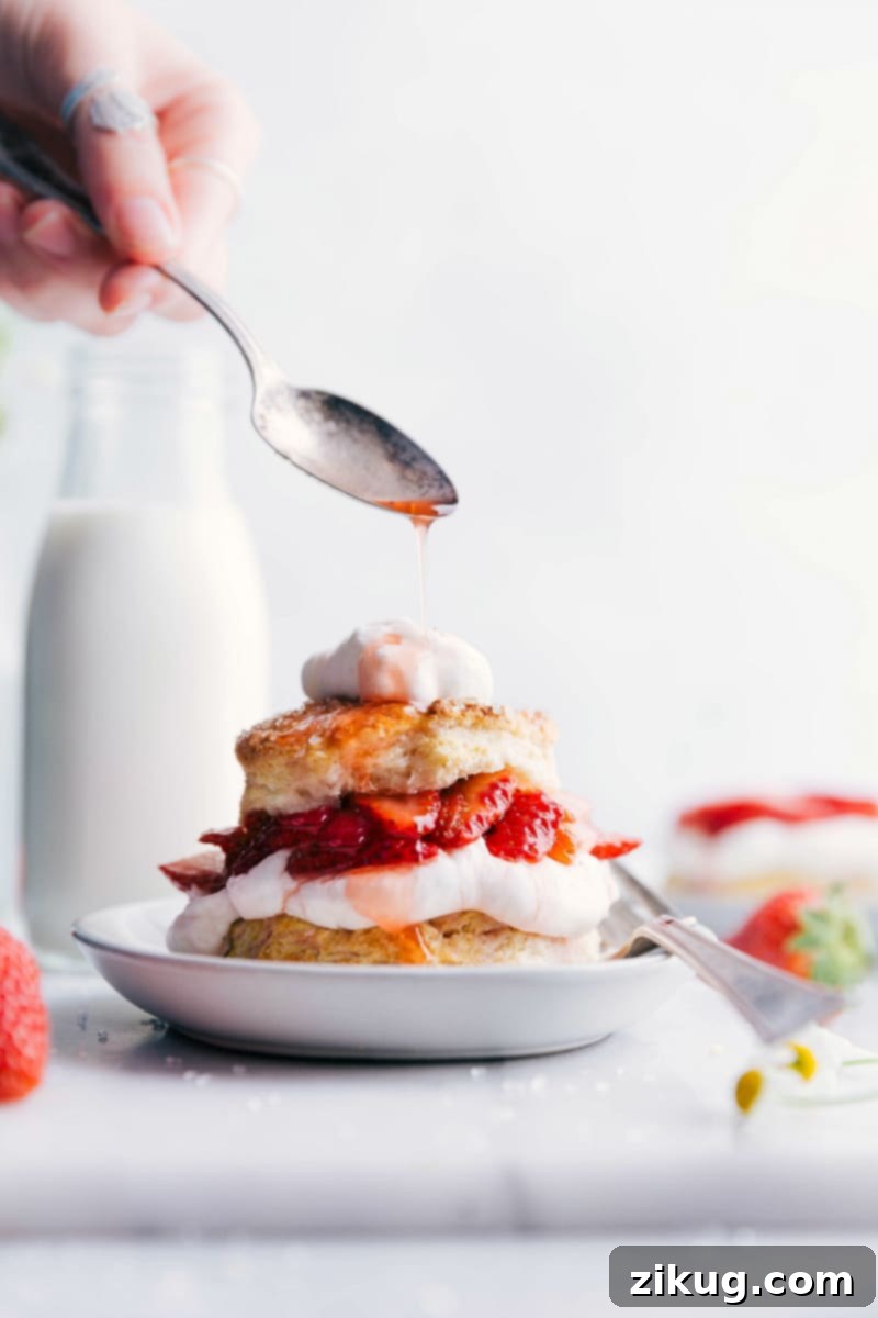Strawberry Shortcake with Drizzled Strawberry Sauce Moist and delicious strawberry shortcake with layers of fluffy cake, fresh strawberries, and whipped cream, strawberry sauce being drizzled on top.