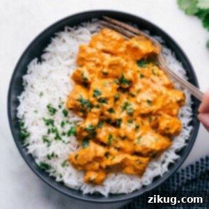 Restaurant-Style Chicken Tikka Masala Made Simple 5 Bowl of chicken tikka masala served with rice, with a fork digging in, showcasing tender chicken pieces in a creamy, spiced sauce.