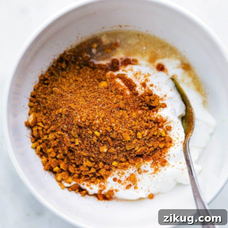 Restaurant-Style Chicken Tikka Masala Made Simple 3 Marinade ingredients, including yogurt, lemon juice, garlic, ginger, and spices, being added to a bowl before being mixed together.