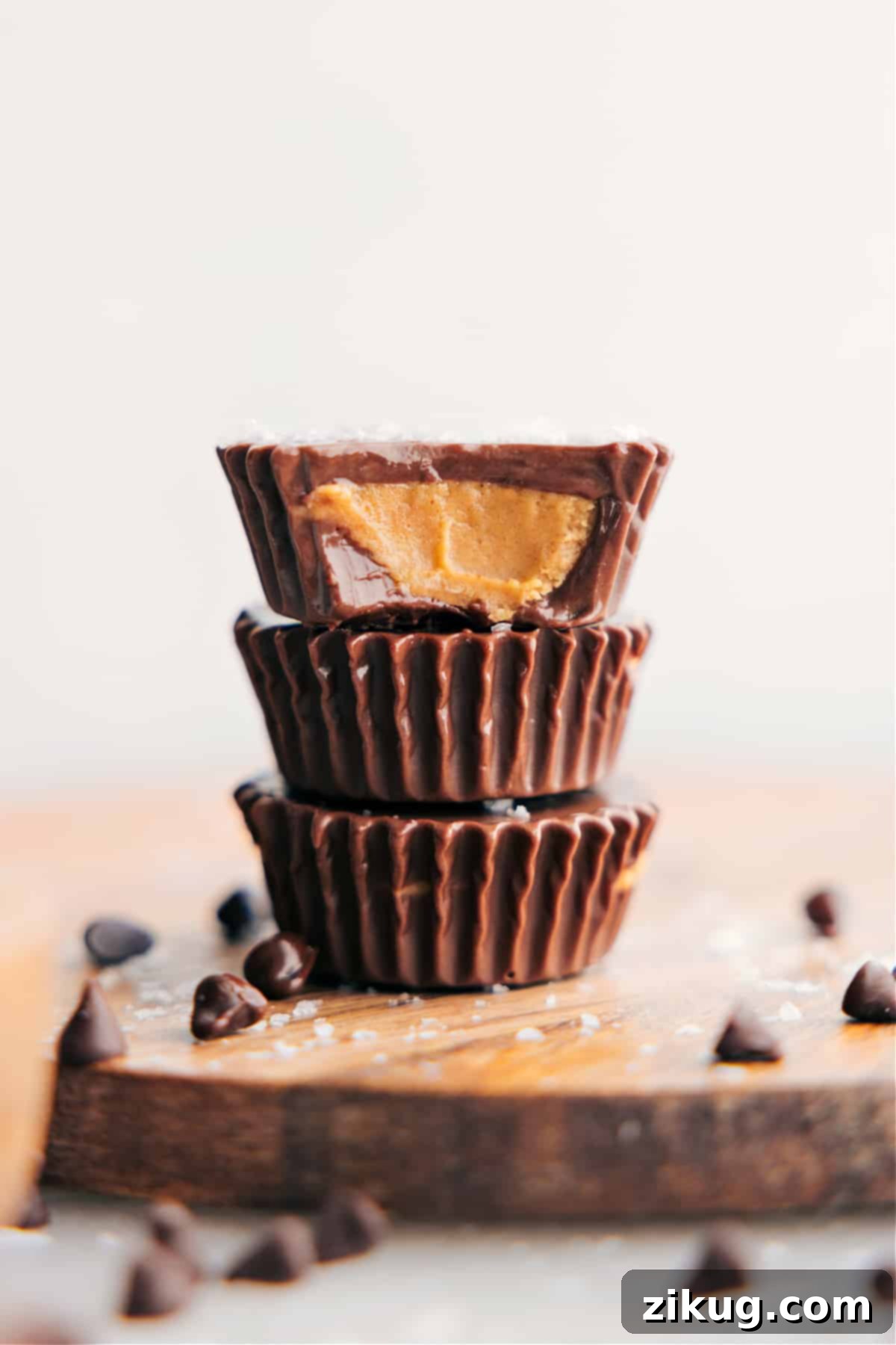 The Best Homemade Peanut Butter Cups Recipe Stacked homemade peanut butter cups with a bite taken out of one, revealing the rich chocolate and creamy peanut butter filling inside.