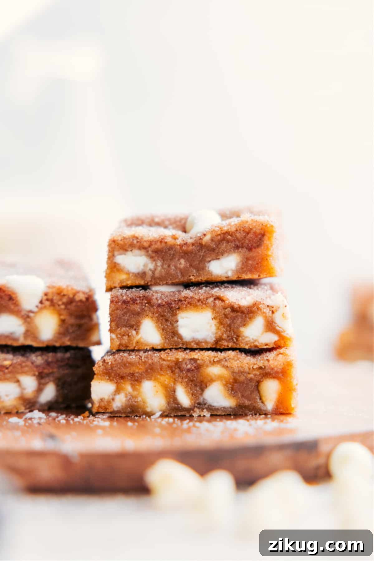 The best Snickerdoodle Blondies stacked on top of each other, perfectly golden and dusted with cinnamon sugar, ready to be enjoyed.