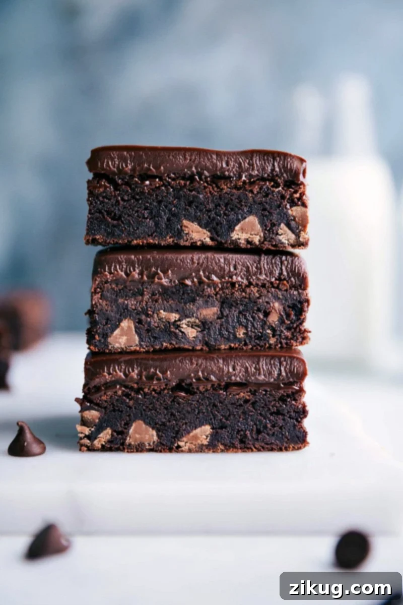 Stacked Gluten-Free Brownies: Fudgy, Rich, and Packed with Chocolate Chips Three perfectly stacked gluten-free brownies, revealing their luscious, fudgy interior studded with melted chocolate chips, promising an irresistible bite.