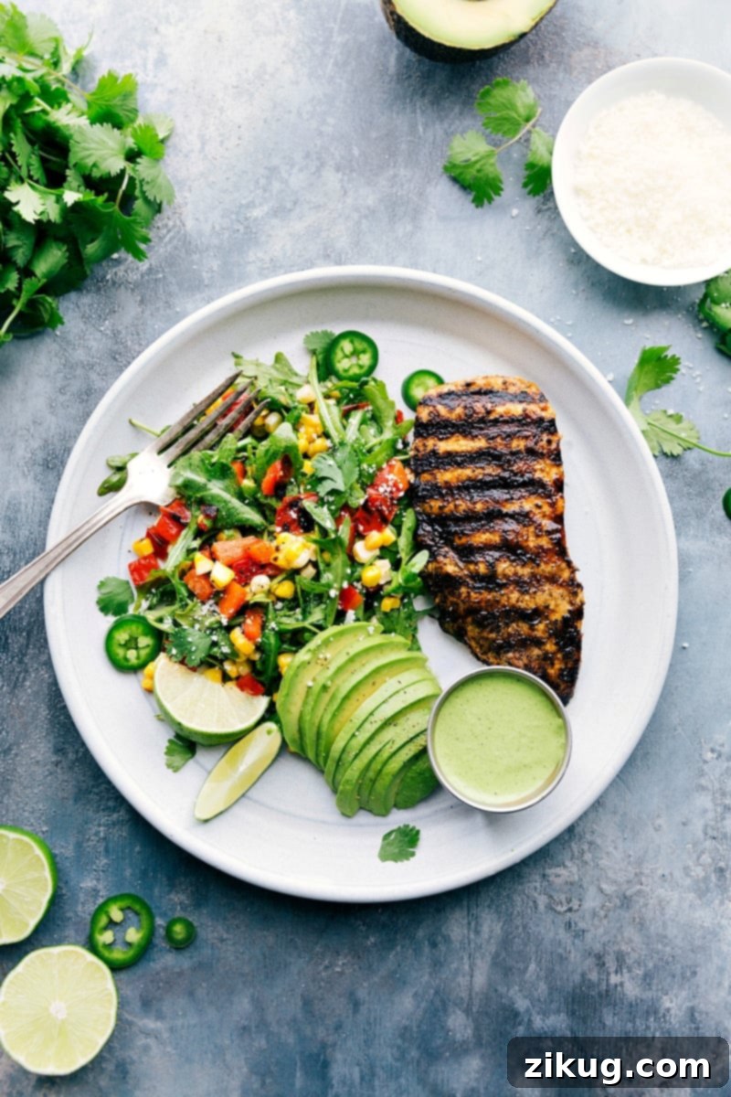 Exquisite Peruvian Chicken Plate with Fresh Salad and Avocado A beautifully plated Peruvian chicken dish featuring perfectly grilled chicken, a vibrant arugula and corn salad, creamy avocado slices, and a generous drizzle of the signature green sauce, highlighting a healthy and flavorful meal option.