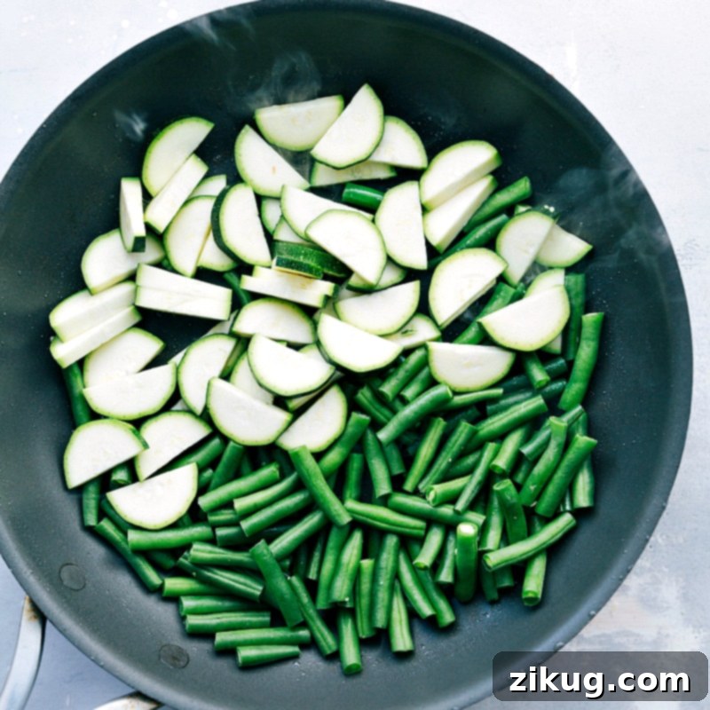 Pre-Sauté Stage: Fresh Zucchini and Green Beans in a Skillet Fresh, uncooked zucchini slices and green beans ready to be sautéed in a hot skillet, showcasing their vibrant natural colors.