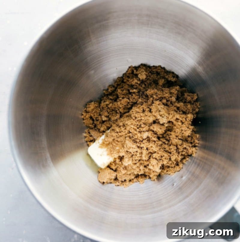 Creaming Brown Sugar and Butter Together Rich dark brown sugar and softened butter are expertly creamed together in a mixing bowl, ready for the next steps in creating delicious cookies.