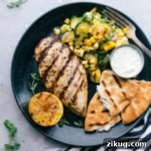 Zesty Greek Lemon Chicken 3 A plate featuring Greek chicken served with naan bread and a zucchini and corn salad, offering a delicious and flavor-packed meal.