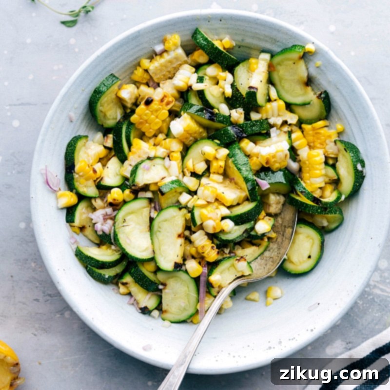 Vibrant Grilled Corn and Zucchini Salad A vibrant bowl of grilled corn and zucchini salad, beautifully charred and seasoned, serving as a fresh and flavorful side dish for the Greek chicken recipe. It highlights the simplicity and deliciousness of Mediterranean cuisine.