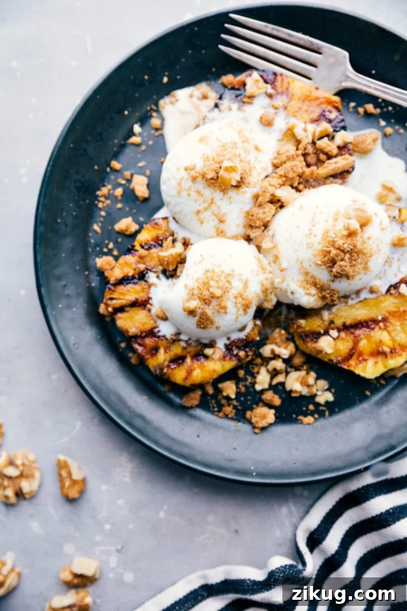 A delightful grilled pineapple sundae topped with vanilla frozen yogurt and a crunchy walnut-graham cracker crumble, showcasing a perfect blend of warm and cold elements, ideal for a refreshing summer dessert.