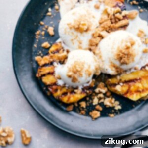 A vibrant grilled pineapple sundae, featuring warm caramelized pineapple slices topped with a generous scoop of vanilla frozen yogurt and a crunchy walnut-graham cracker crumble, highlighting the warm-cold contrast and rich textures.